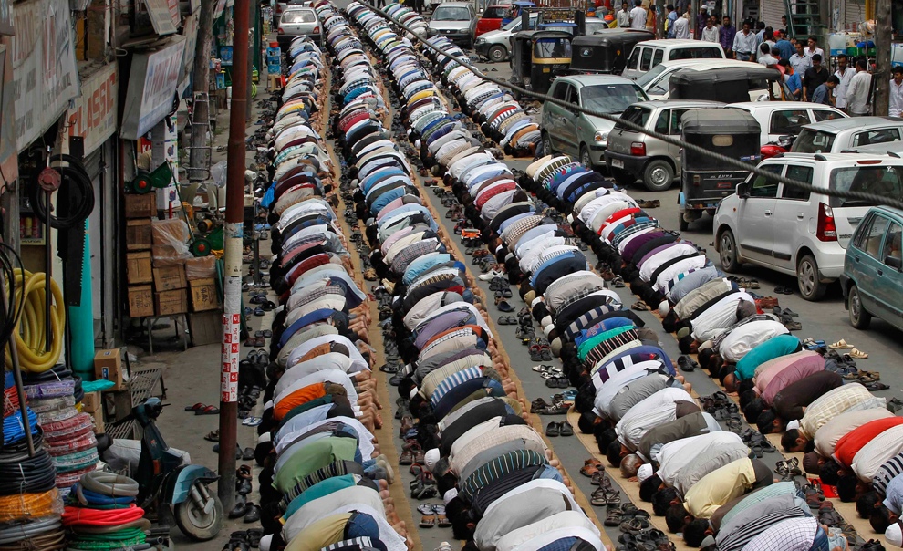 Кашмирские мусульмане молятся рядом с припаркованными автомобилями