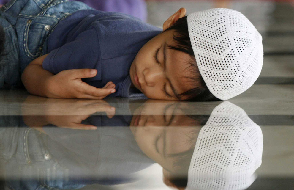 Индонезия, Макассар. Мальчик заснул на полу в мечети в ожидания разговения в первый день священного месяца Рамадана