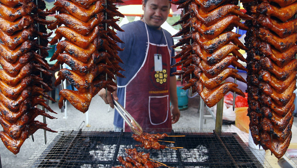 Мужчина в Малайзии жарит крылья курицы для разговения