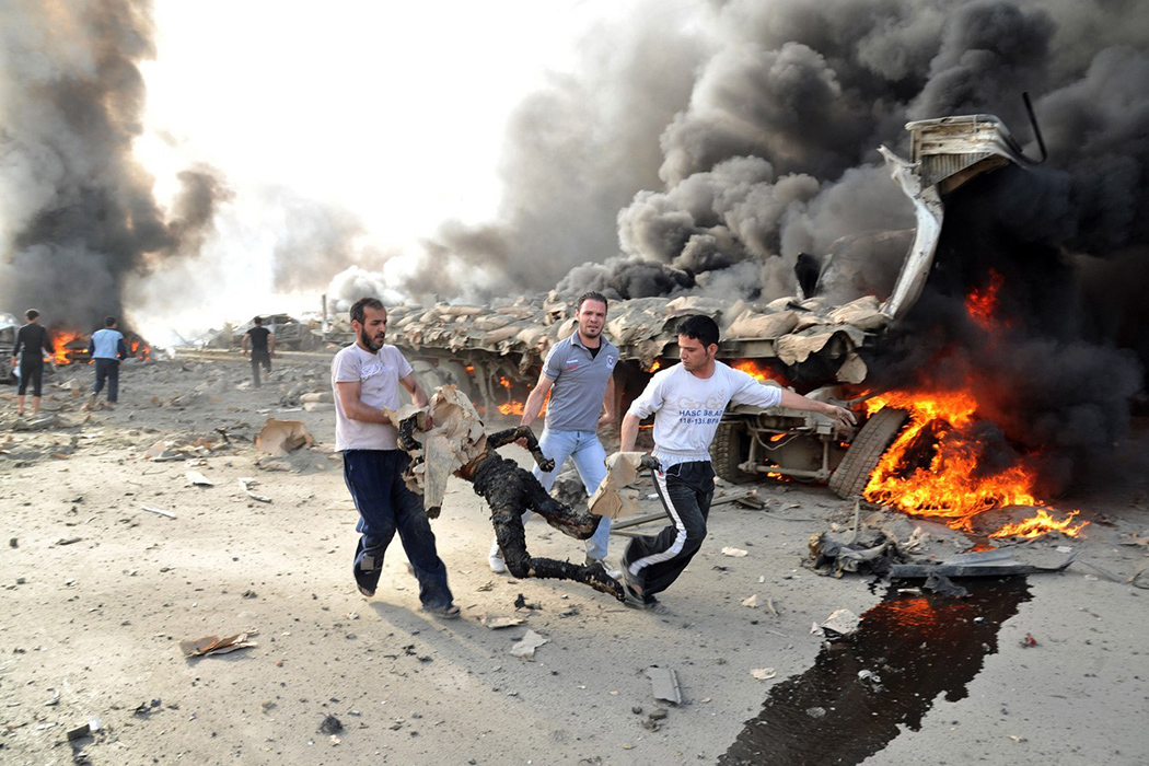 Люди бегут, неся обгоревшее тело на месте взрыва в Дамаске