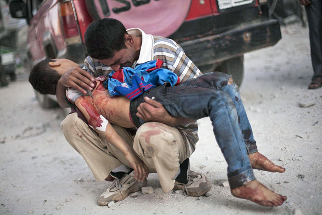 Сирийский мужчина плачет, держа на руках тело своего сына, возле больницы Дар Эль Шифа