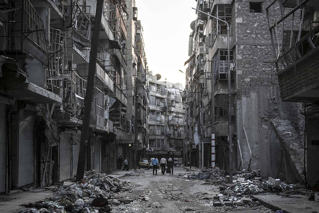 Сирийцы идут по улице среди разрушенных зданий на юго-востоке Алеппо 