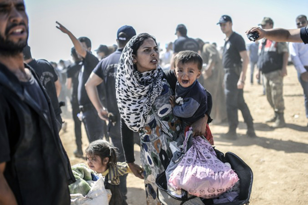 Сирийская курдянка с детьми пересекает границу с Турцией