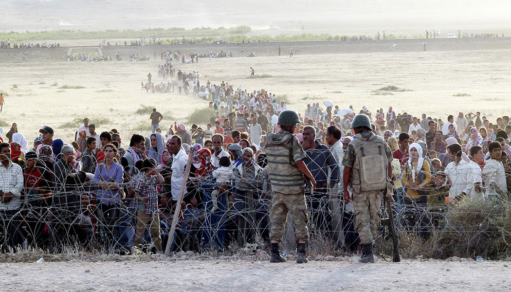 Сирийские курды стоят в ожидании возле пограничных ограждений