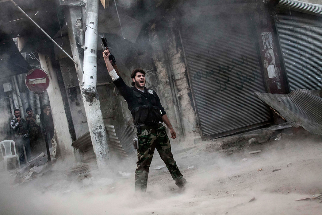 Повстанец стреляет в воздух в качестве сигнала о победе над сирийскими солдатами