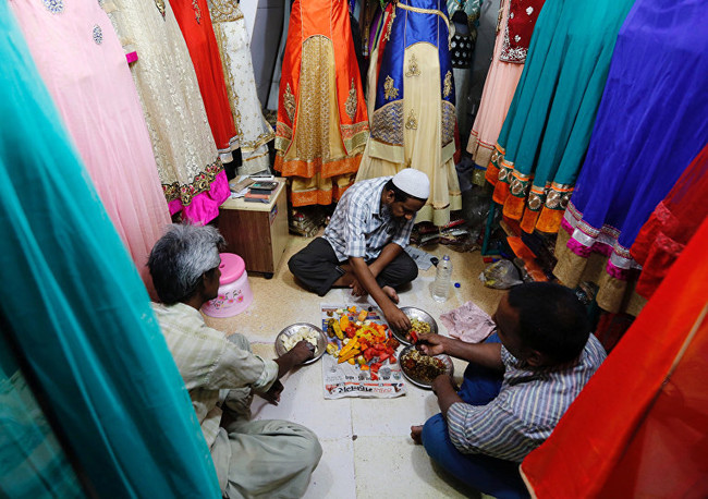 Продавцы вкушают ифтар в своем магазине одежды